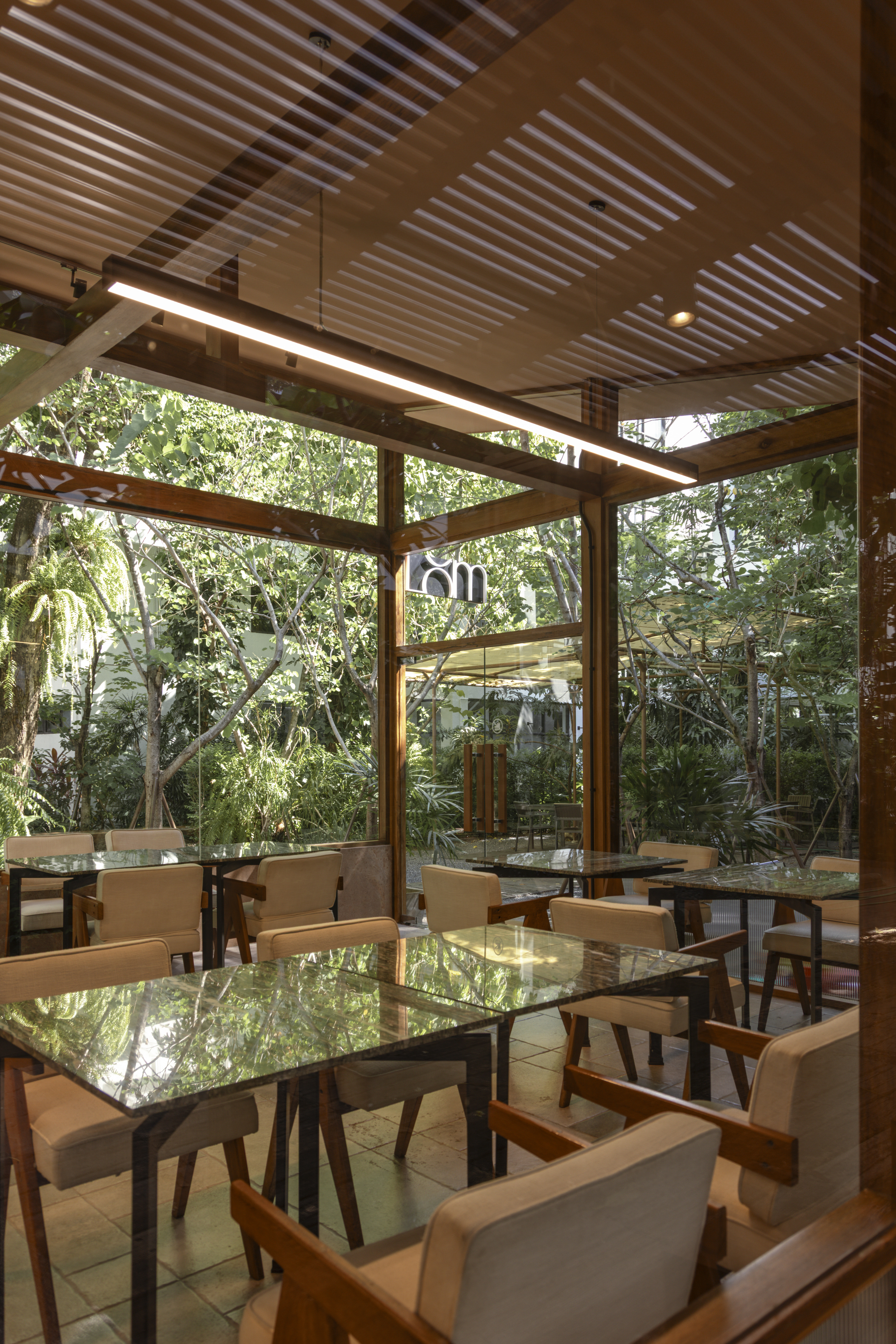 Café LOM dining room with garden trees through glass walls